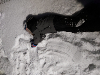 Dziewczynka leżąca w śniegu trzymające ręce w górze