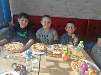 zadowoleni chłopcy jedzą pizzę