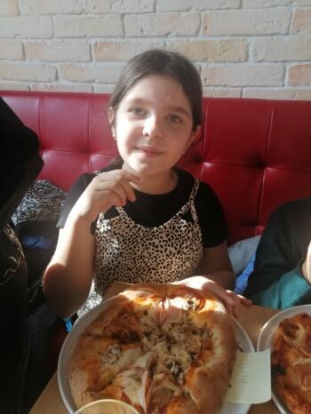 dziewczynka z pizzą na talerzu