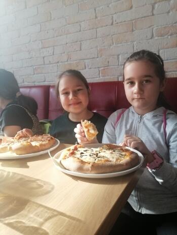 dwie dziewczynki jedzące pizzę