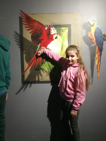 Dziewczynka z obrazem 3d w tle z papugą
