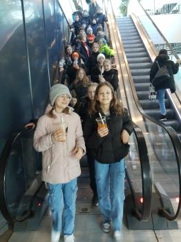 uczniowie schodzą z ruchomych schodów w centrum handlowym