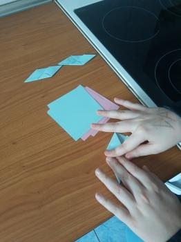 uczeń sz niebieskiej kartki składa origami modułowe