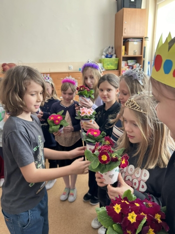 Uczniowie klasy 3 d wręczający koleżankom kwiaty z okazji Dnia Kobiet