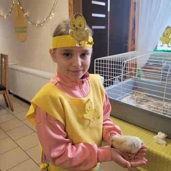 Uśmiechnięta dziewczynka z kurczaczkiem w ręku