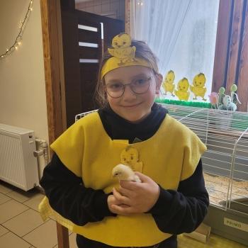 Uśmiechnięta dziewczynka z kurczaczkiem na rękach 