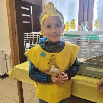 Uśmiechnięty chłopiec kurczaczkiem w rękach 