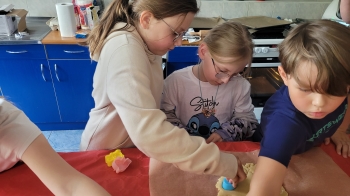 Dzieci wykrawają foremkami ciastka 