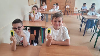 Uśmiechnięci chłopcy trzymają klatki z pszczołami  